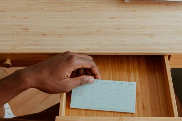 Handen ordenen een bureaulade met schrijfgerei