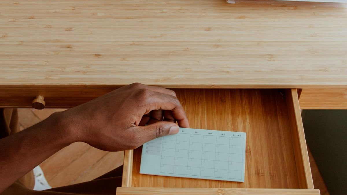 Handen ordenen een bureaulade met schrijfgerei