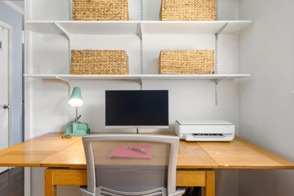 Smal bureau tegen de muur met planken en manden erboven
