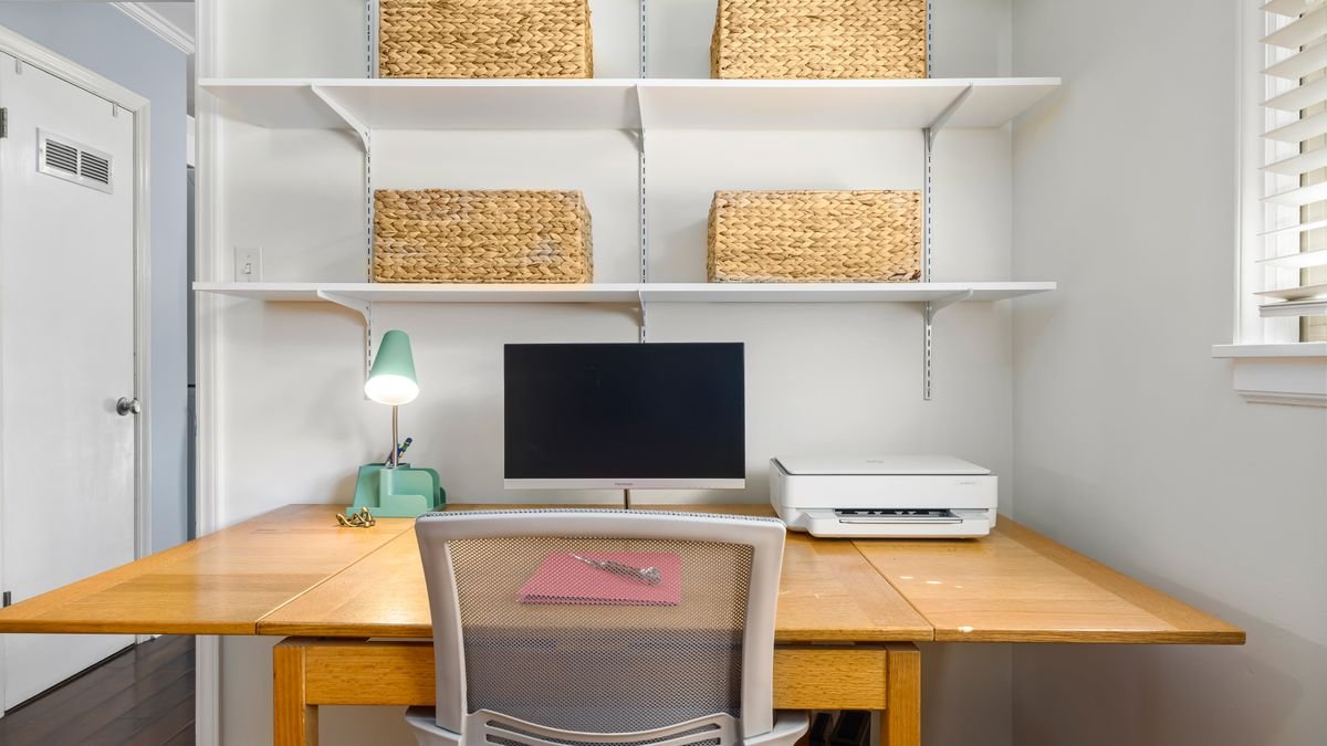 Smal bureau tegen de muur met planken en manden erboven