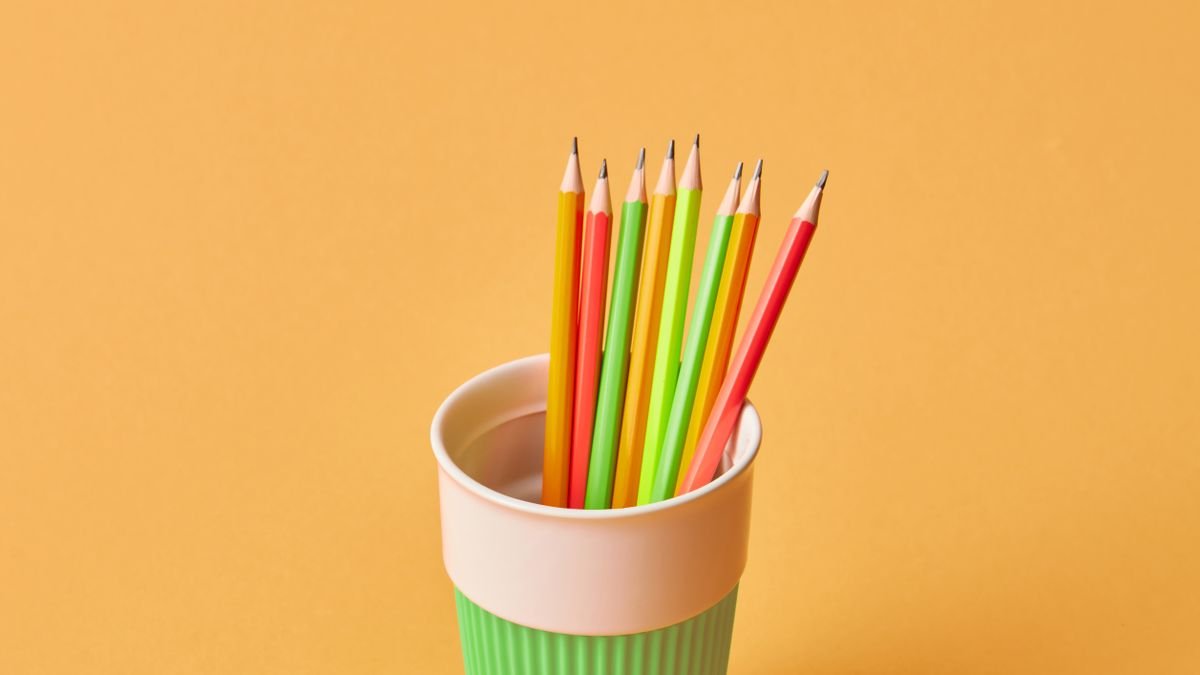 Groene pennenbeker tegen oranje achtergrond