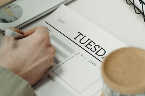 Persoon schrijft in een planner op het bureau