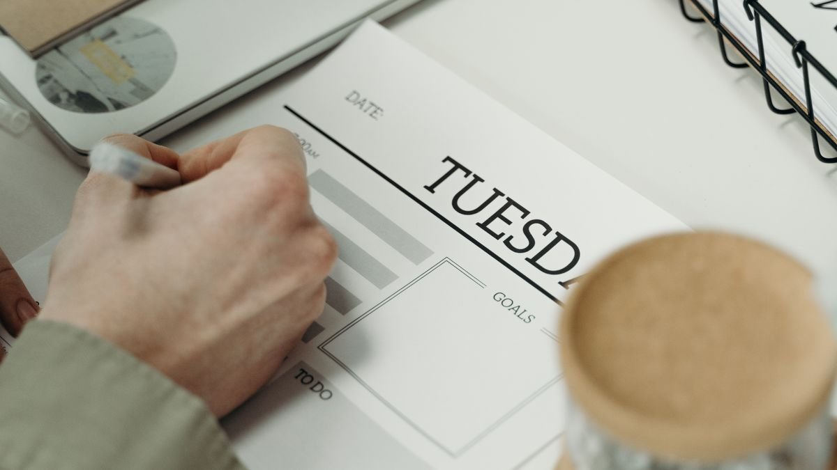 Persoon schrijft in een planner op het bureau