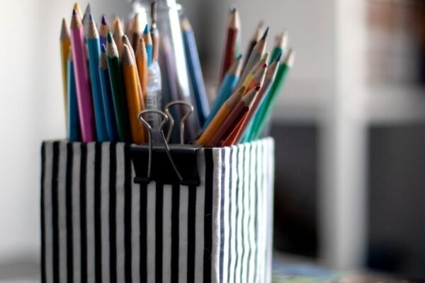 Gestreepte pennenhouder met kleurpotloden op schoolbureau