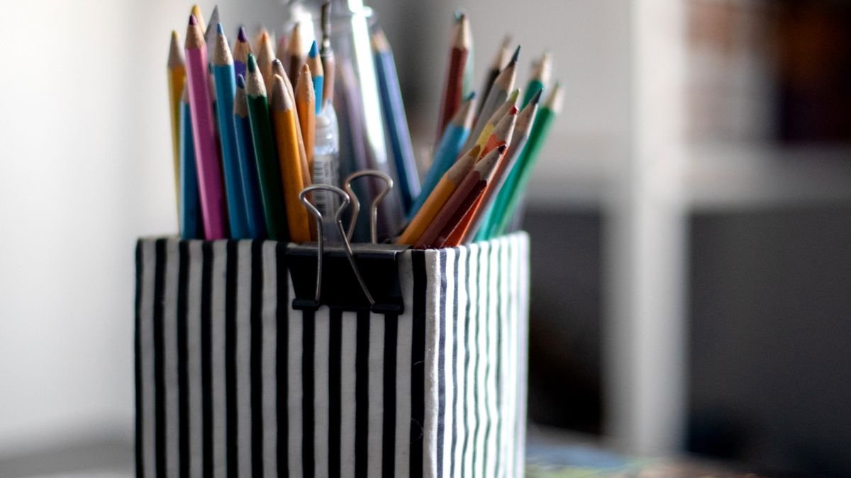 Gestreepte pennenhouder met kleurpotloden op schoolbureau
