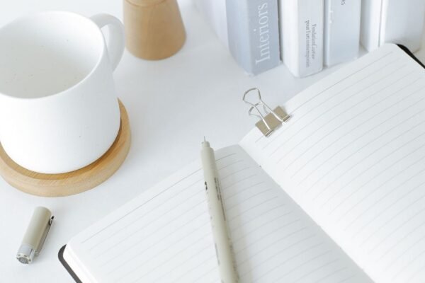 Opgeruimd bureau met notitieboek, boeken en een kop koffie