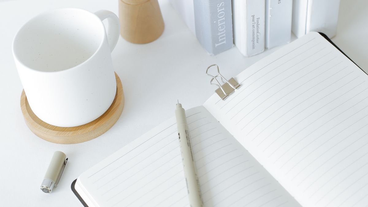 Opgeruimd bureau met notitieboek, boeken en een kop koffie