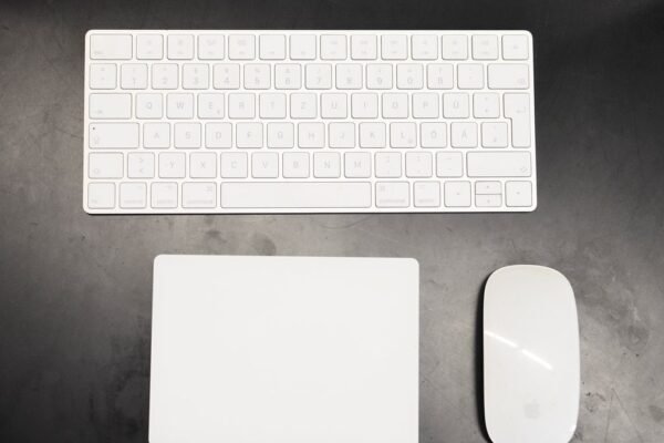 Wit draadloos toetsenbord, trackpad en muis op een donker bureau