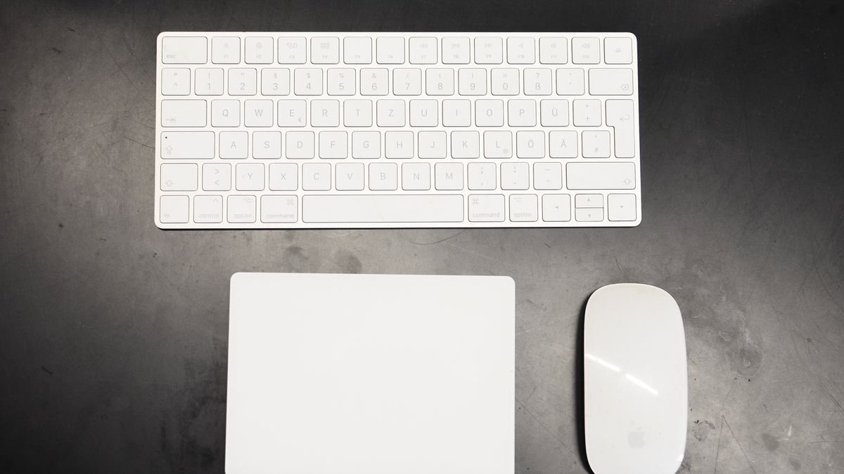 Wit draadloos toetsenbord, trackpad en muis op een donker bureau