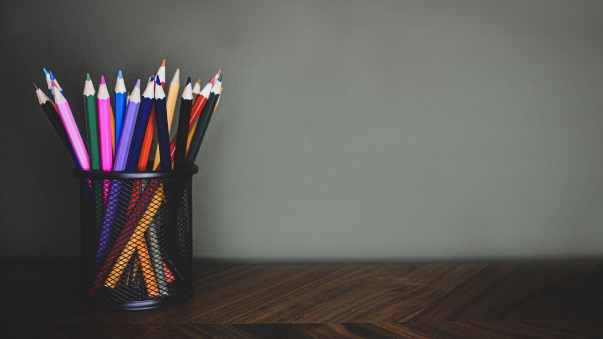 Kleurpotloden in zwarte mesh pennenbak op donker houten bureau
