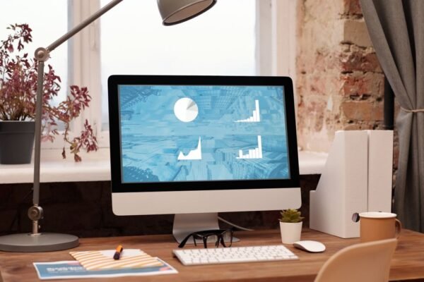 Werkplek met iMac, bureaulamp en plant bij een bakstenen muur