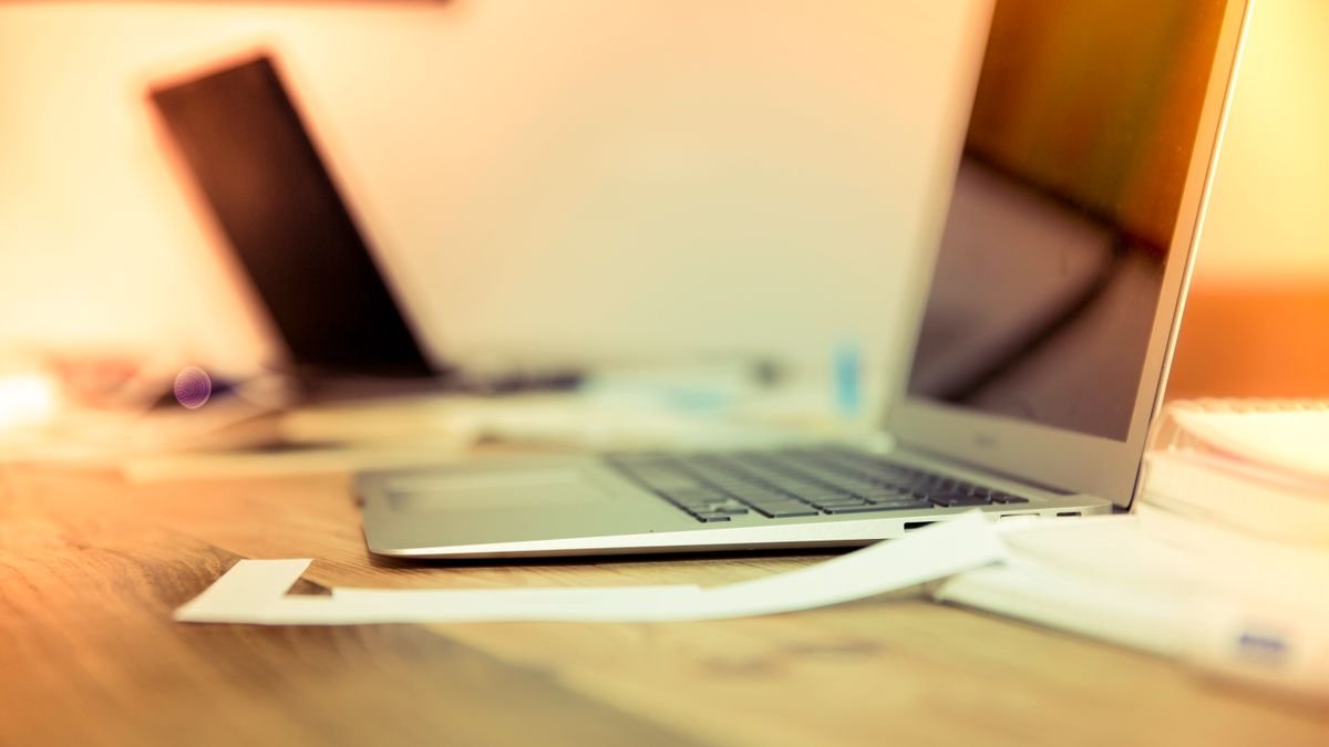 Laptop en papieren op een houten tafel bij daglicht