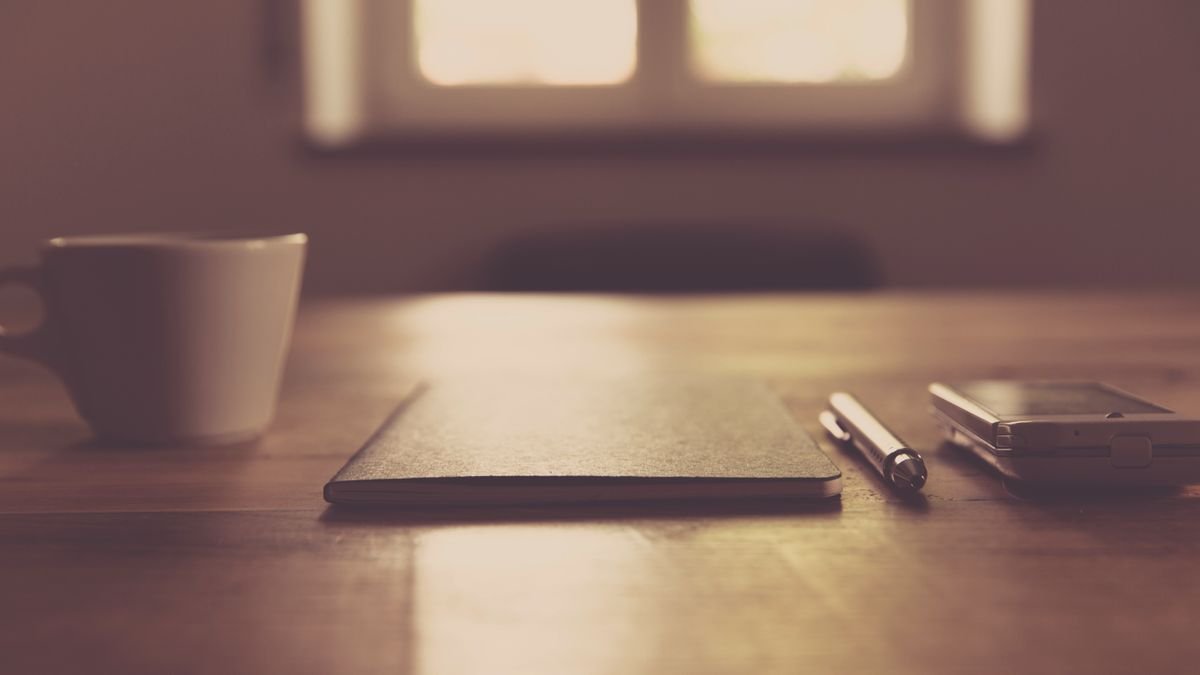 Kop koffie naast smartphone en notitieboek op bureau