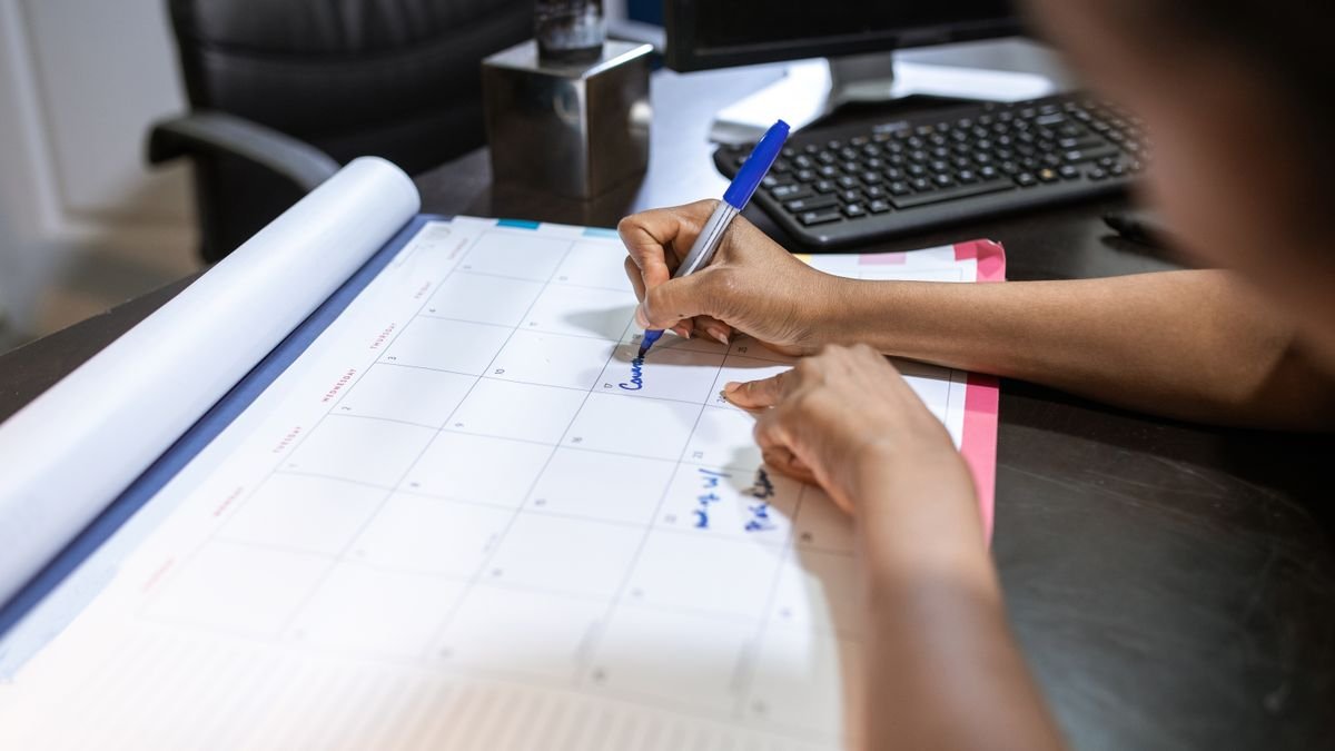 Iemand schrijft op een bureaukalender