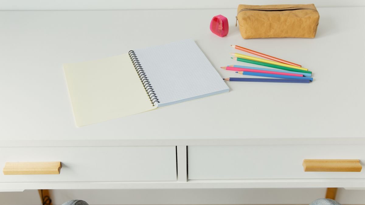 Notitieboek met kleurpotloden op wit kinderbureau