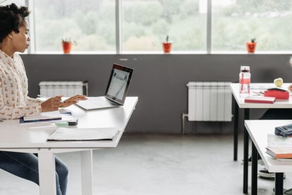 Leerkracht aan haar bureau met laptop in een klaslokaal