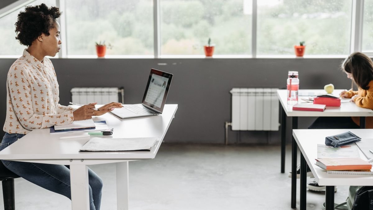 Leerkracht aan haar bureau met laptop in een klaslokaal