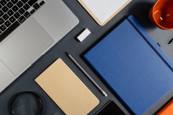 Plat neergelegde laptop, notitieboeken en kleine schrijfwaren