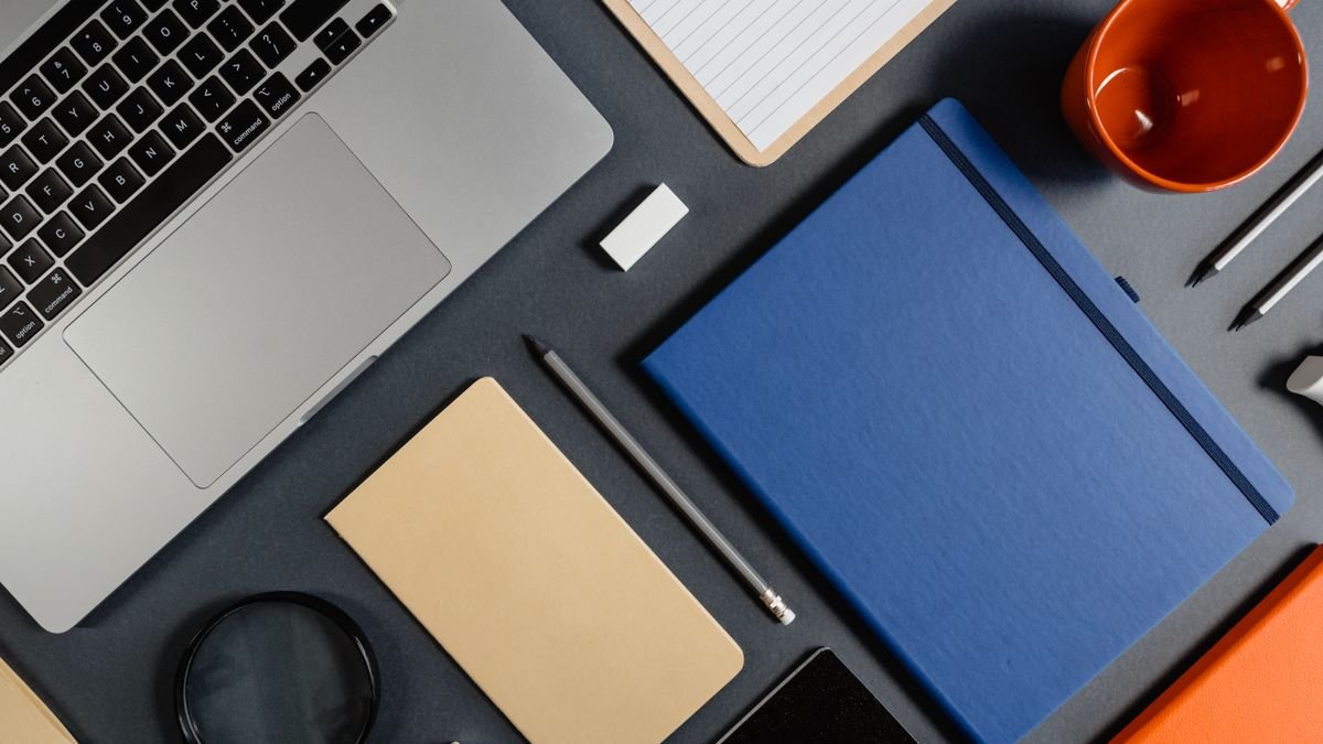 Plat neergelegde laptop, notitieboeken en kleine schrijfwaren