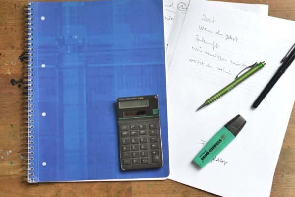 Ringmap, rekenmachine, pennen en markeerstift op een houten bureau