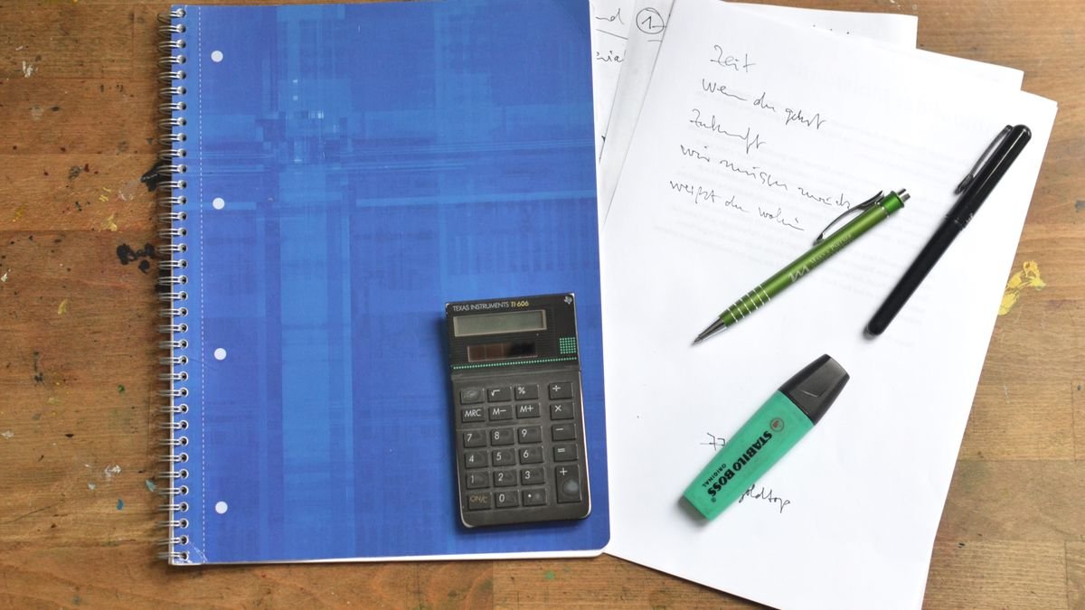 Ringmap, rekenmachine, pennen en markeerstift op een houten bureau