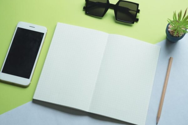 Smartphone, printpapier, zonnebril en potlood plat neergelegd