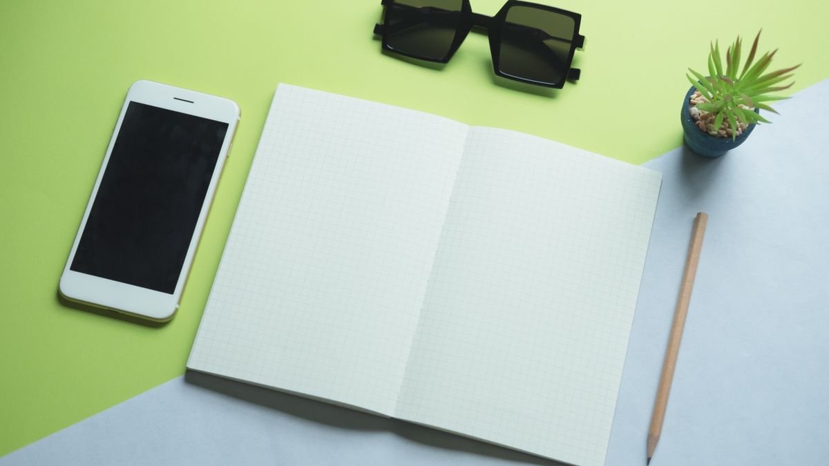 Smartphone, printpapier, zonnebril en potlood plat neergelegd