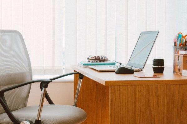 Bureau met bureaustoel en kantoorspullen bij het raam