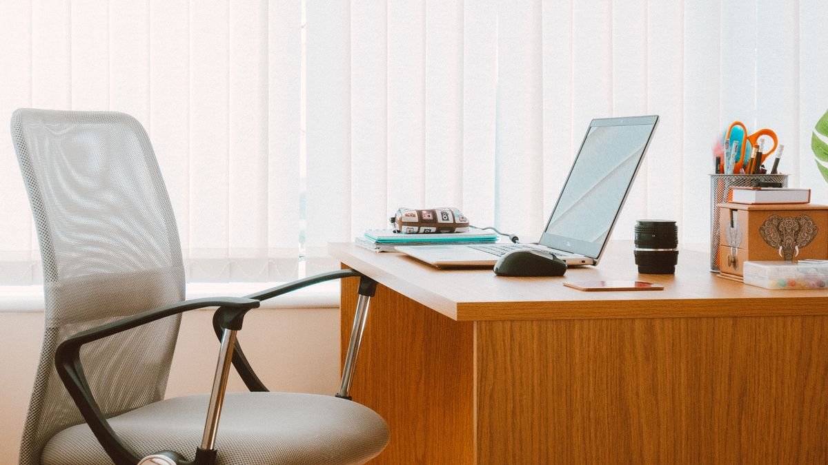 Bureau met bureaustoel en kantoorspullen bij het raam
