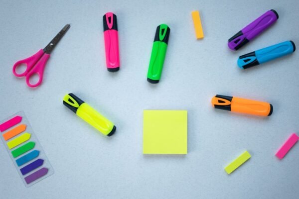 Markeerstiften, schaar en post-its op een blauwe ondergrond