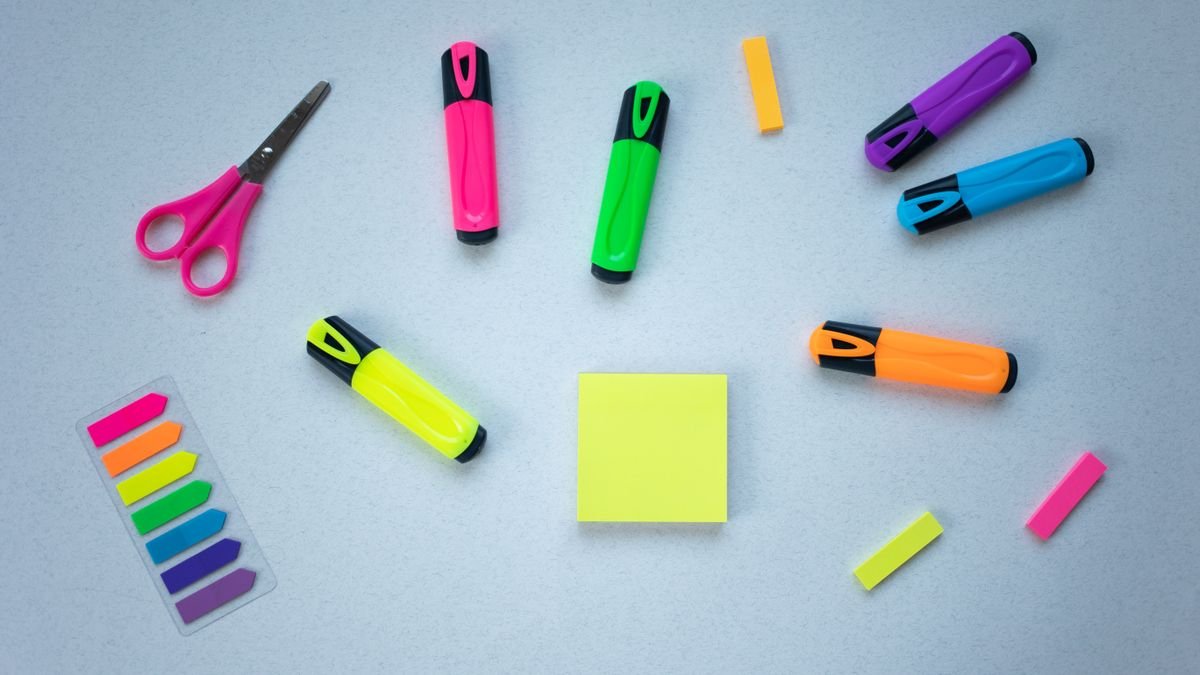 Markeerstiften, schaar en post-its op een blauwe ondergrond